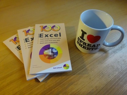 Photo of the book 100 Top Tips Microsoft Excel, next to a mug that says I Heart Spreadsheets on it.