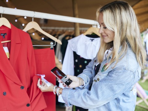 Photo of Fearne Cotton using her phone to scan a label on a red jacket