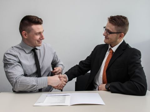 Photo of two men shaking hands over a contract
