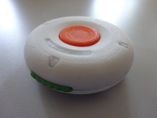 The prototype ScratchGo device, like a pellet with a button on the top and a button on the side