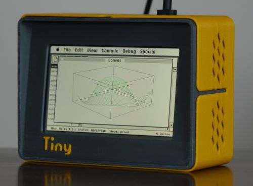 Photo of yellow-cased screen with TinyProgrammer written on the front, with the screen showing a 3D plot with an early Mac computer interface