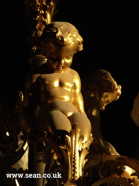 Photo of a dusty gold light fitting, in the Louvre in Paris, France
