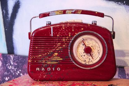 A photo of a bright-red, plastic, paint-splattered radio.