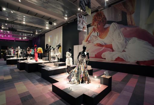 Photo of the exhibition floor, with big picture of Kylie behind mannequins modelling her clothes